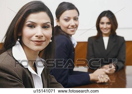 Stock Image - Portrait of three businesswomen sitting in a conference room. Fotosearch