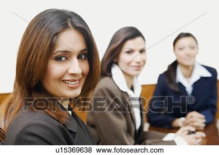 Stock Photo - Portrait of three businesswomen sitting in a conference room. Fotosearch