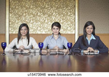 Stock Photograph - Portrait of three businesswomen sitting in a conference room. Fotosearch