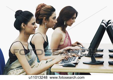 Side profile of three businesswomen working on computers in an office View Large Photo Image Stock Photo - Side profile of three businesswomen working on computers in an office. Fotosearch