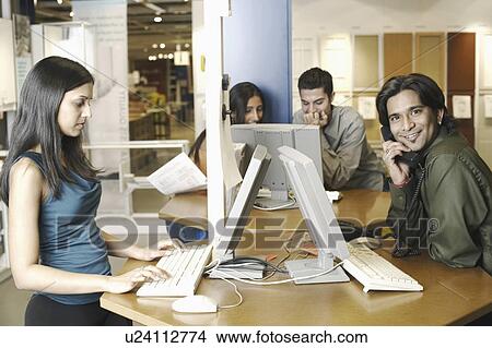 Two businessmen and two businesswomen working in an office View Large Photo Image Picture - Two businessmen and two businesswomen working in an office. Fotosearch