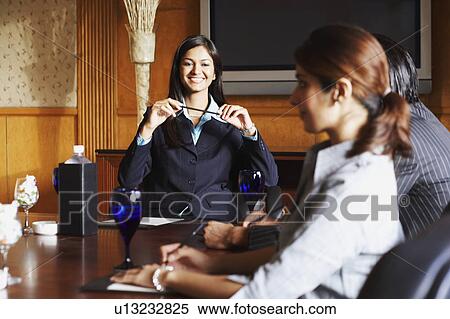 Stock Photography - Two businesswomen and a businessman sitting in a conference room and discussing. Fotosearch