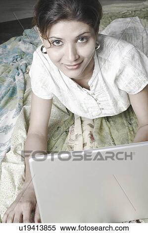 Stock Photography - High angle view of a young woman in front of a laptop. Fotosearch