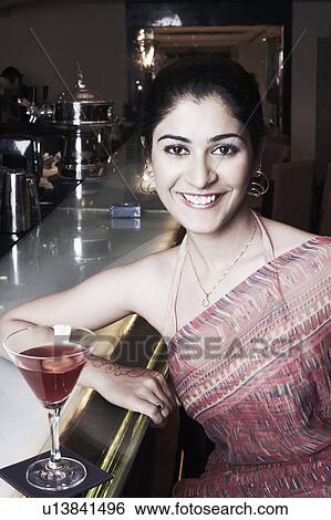 Stock Photograph - Portrait of a businesswoman at a bar counter with a martini glass. Fotosearch