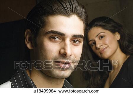Picture - Portrait of a young man grinning with a young woman behind him. Fotosearch