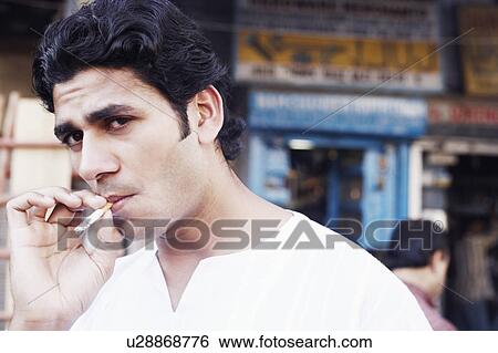 Portrait of a young man smoking a cigarette View Large Photo Image Stock Photograph - Portrait of a young man smoking a cigarette. Fotosearch