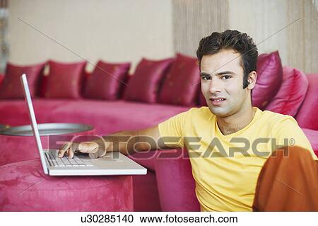 Stock Image - Portrait of a young man using a laptop. Fotosearch