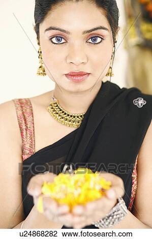 Stock Image - Portrait of a young woman holding flowers in her palm. Fotosearch