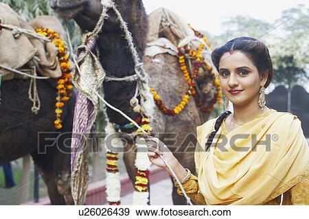 Stock Photo - Portrait of a young woman holding the rein of a camel. Fotosearch