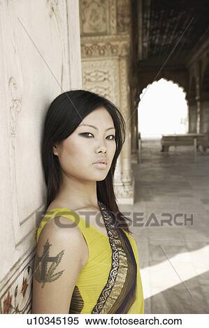 Stock Photography - Portrait of a young woman leaning against a wall. Fotosearch