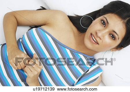 Stock Photo - Portrait of a young woman lying on her back and smiling. Fotosearch