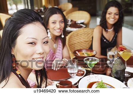 Three young women dining in a restaurant View Large Photo Image Stock Image - Three young women dining in a restaurant. Fotosearch