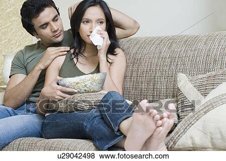 Stock Photo - Young woman crying and young man sitting behind her. Fotosearch