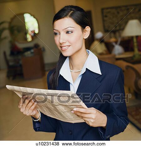 Stock Photo - Close-up of a businesswoman holding a newspaper. Fotosearch