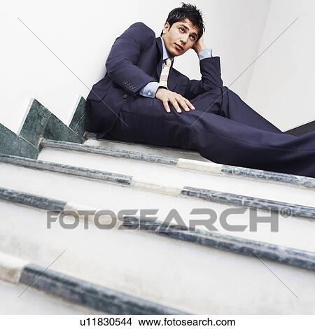 Low angle view of a businessman sitting on the staircase View Large Photo Image Picture - Low angle view of a businessman sitting on the staircase. Fotosearch