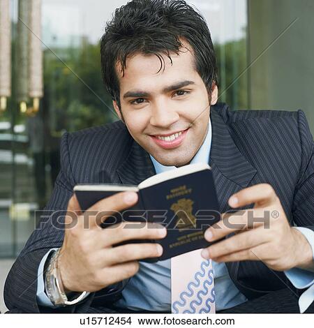 Picture - Portrait of a businessman holding a passport and smiling. Fotosearch