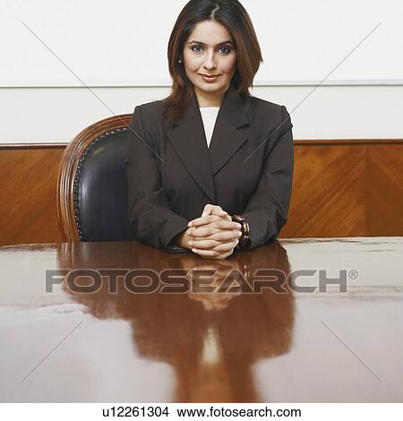 Picture - Portrait of a businesswoman sitting in a conference room with her hands clasped. Fotosearch
