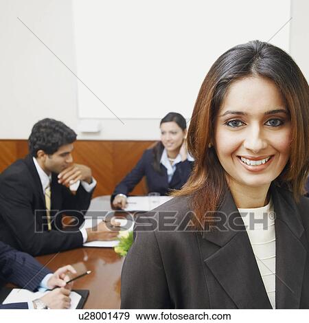 Stock Photo - Portrait of a businesswoman with three business executives sitting behind her. Fotosearch