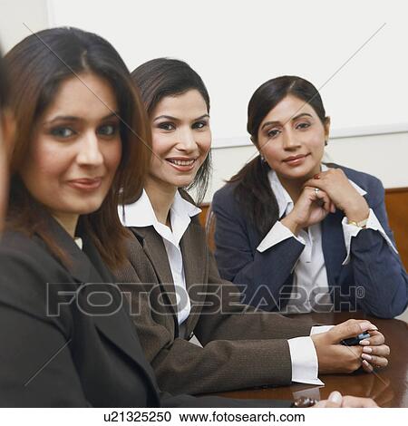Stock Image - Portrait of three businesswomen sitting in a conference room. Fotosearch