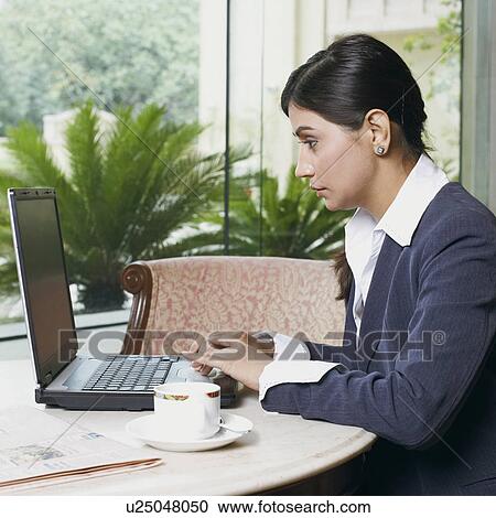 Stock Image - Side profile of a businesswoman working on a laptop. Fotosearch