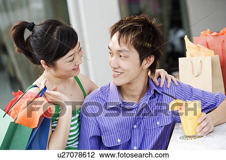 Stock Image - Close-up of a young couple looking at each other and smiling. Fotosearch