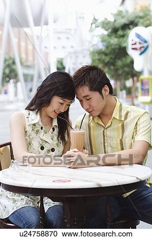 Close-up of a young couple sitting in a cafeteria View Large Photo Image Stock Image - Close-up of a young couple sitting in a cafeteria. Fotosearch