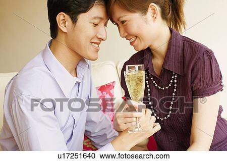 Close-up of a young couple smiling and toasting champagne flutes View Large Photo Image Stock Image - Close-up of a young couple smiling and toasting champagne flutes. Fotosearch