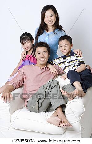 Portrait of a mid adult man and a young woman sitting in an armchair with their son and daughter View Large Photo Image Stock Photo - Portrait of a mid adult man and a young woman sitting in an armchair with their son and daughter. Fotosearch
