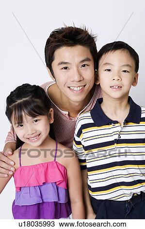 Stock Image - Portrait of a mid adult man smiling with his son and daughter. Fotosearch