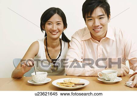 Stock Photography - Portrait of a young couple sitting together and smiling. Fotosearch