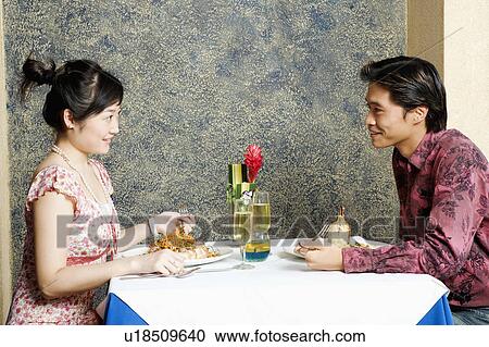 Side profile of a young couple sitting in a restaurant View Large Photo Image Stock Image - Side profile of a young couple sitting in a restaurant. Fotosearch