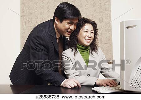 Stock Photo - Businessman and a businesswoman using a computer. Fotosearch