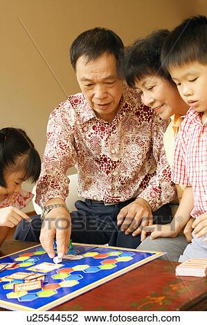 Stock Image - Close-up of a girl and a boy playing a game with their grandparents. Fotosearch