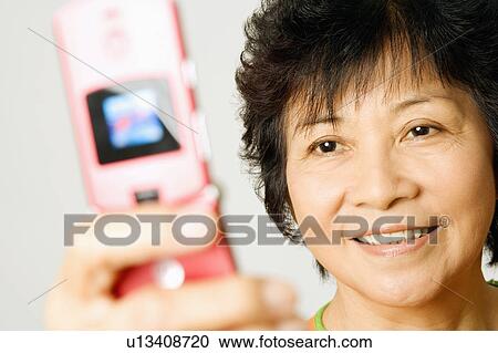 Stock Image - Close-up of a mature woman holding a mobile phone. Fotosearch