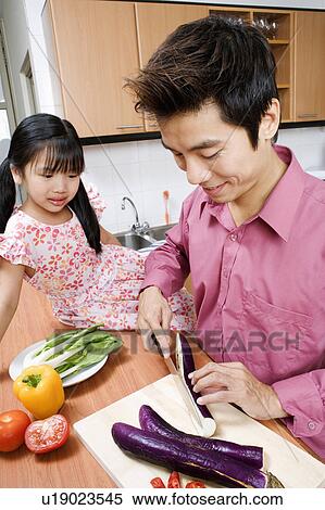 Close-up of a mid adult man and his daughter cutting vegetables at a kitchen counter View Large Photo Image Stock Photography - Close-up of a mid adult man and his daughter cutting vegetables at a kitchen counter. Fotosearch