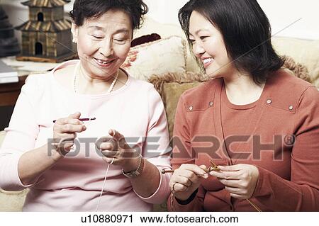 Stock Image - Close-up of a mother and her daughter knitting. Fotosearch
