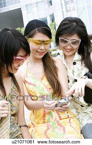 Close-up of three young women looking at a mobile phone View Large Photo Image Stock Image - Close-up of three young women looking at a mobile phone. Fotosearch
