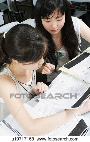 High angle view of a young woman and a teenage girl reading notes in the classroom View Large Photo Image Stock Photo - High angle view of a young woman and a teenage girl reading notes in the classroom. Fotosearch