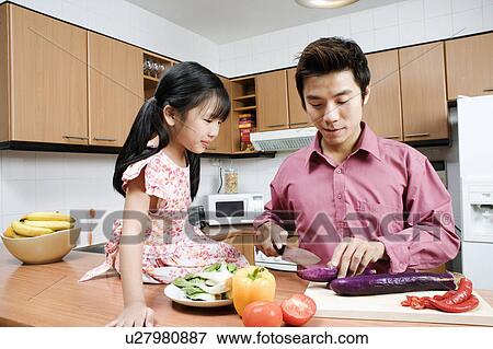 Mid adult man and his daughter cutting vegetables at a kitchen counter View Large Photo Image Stock Photo - Mid adult man and his daughter cutting vegetables at a kitchen counter. Fotosearch
