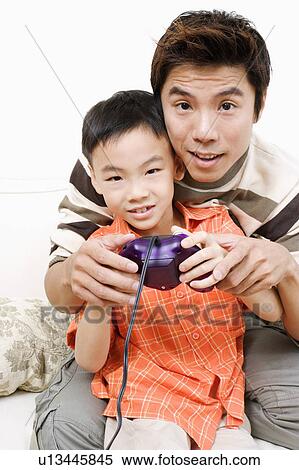 Portrait of a boy and his father playing a video game View Large Photo Image Stock Photography - Portrait of a boy and his father playing a video game. Fotosearch