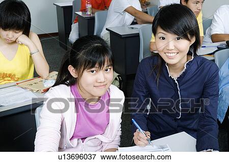 Stock Photo - Portrait of a girl filling out a form with her teacher's help. Fotosearch