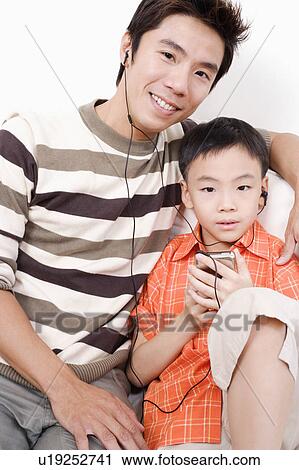 Portrait of a mid adult man and his son listening to an MP3 player View Large Photo Image Stock Image - Portrait of a mid adult man and his son listening to an MP3 player. Fotosearch