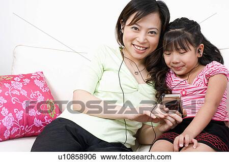 Portrait of a young woman and her daughter listening to an MP3 player View Large Photo Image Stock Photograph - Portrait of a young woman and her daughter listening to an MP3 player. Fotosearch