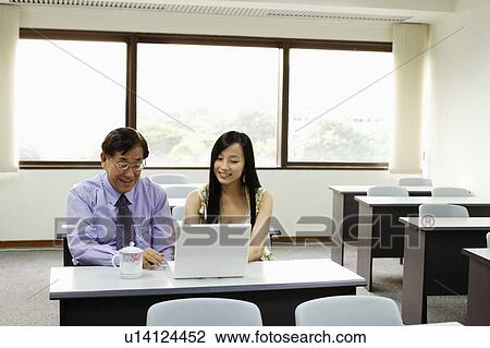 Stock Image - Senior man and a young woman using a laptop. Fotosearch