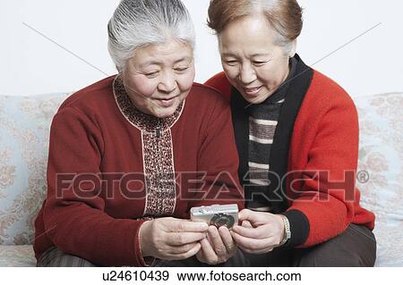 Senior woman sitting with a mature woman holding a digital camera View Large Photo Image Stock Photo - Senior woman sitting with a mature woman holding a digital camera. Fotosearch