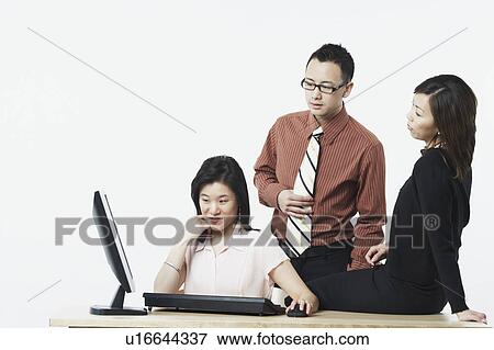 Stock Photo - Two businesswomen and a businessman looking at a computer monitor. Fotosearch