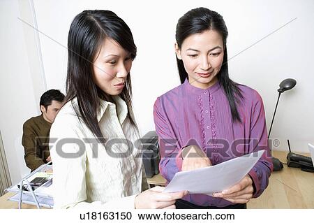 Two businesswomen reading a document View Large Photo Image Stock Image - Two businesswomen reading a document. Fotosearch