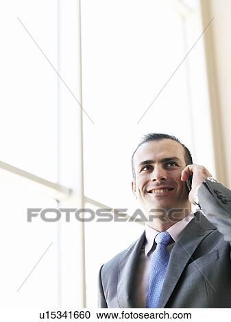 Businessman using mobile phone, smiling, low angle view View Large Photo Image Stock Image - Businessman using mobile phone, smiling, low angle view. Fotosearch