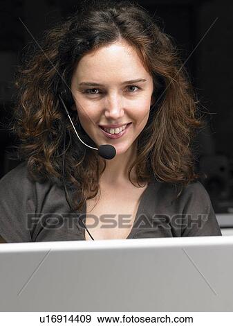 Stock Photo - Businesswoman wearing headset, working on laptop. Brussels, Belgium.. Fotosearch