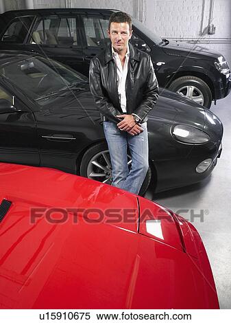 Stock Photography - Man in garage with luxury cars.. Fotosearch